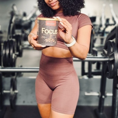 Mulher com roupa desportiva cor de rosa segura lata preta Focus num ginásio