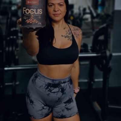 Mulher com roupa desportiva a segurar embalagem de suplemento Coffee Focus