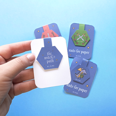 Quatro cartões azuis com ilustrações místicas e texto, um segurado por uma mão sobre fundo azul