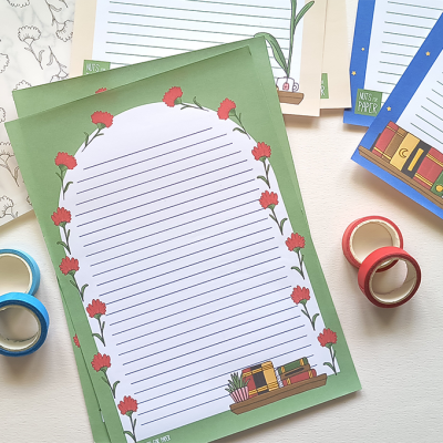 Papéis de carta decorativos com padrões florais e livros, com fitas adesivas azul e vermelha