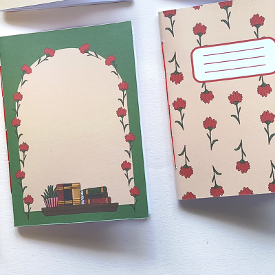 Dois cadernos com capas florais ao lado de um lápis sobre superfície branca