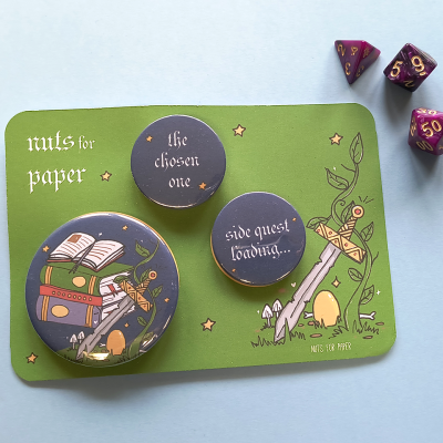 Bottons pretos com texto e ilustrações sobre cartão verde e três dados roxos e dourados num fundo azul claro.