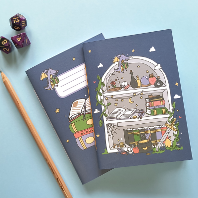 Dois cadernos ilustrados com livros e animais, lápis de madeira e dados coloridos sobre fundo azul