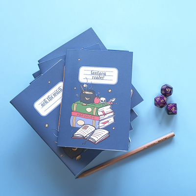 Três cadernos azuis com ilustração de coelho e livros, dados poliédricos roxos e lápis de madeira