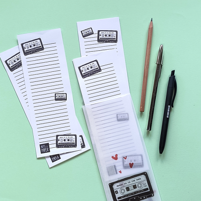 Blocos de notas com cassetes e canetas sobre fundo verde claro