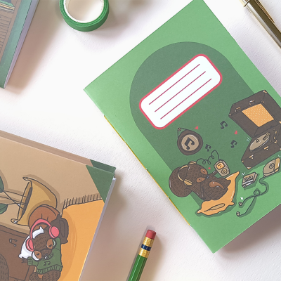 Dois cadernos coloridos com ilustrações de rato e planta junto com fita e caneta