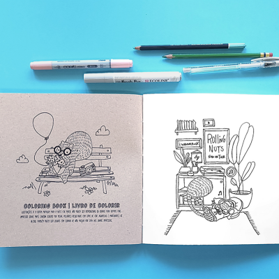 Livro de colorir aberto com desenhos a preto e branco e material de desenho azul no fundo