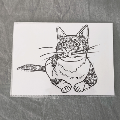 Desenho a preto e branco de gato em papel sobre superfície cinzenta