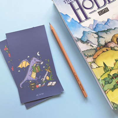 Marcadores de livros com dragão, lápis e livro The Hobbit sobre fundo azul