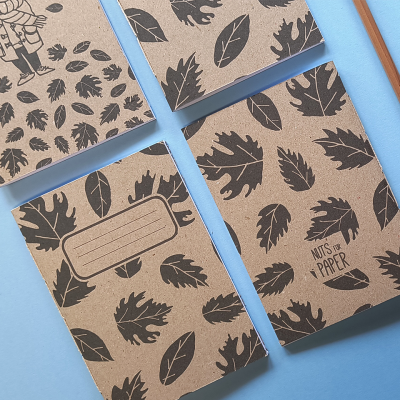 Quatro cadernos reciclados com padrões de folhas e texto 'NUTS ON PAPER'