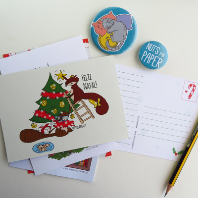 Postais de Natal com ilustrações e bottons coloridos sobre mesa branca