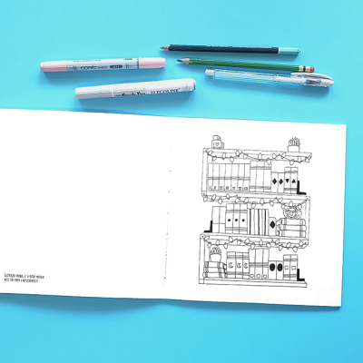 Caderno aberto com desenho de estantes de xadrez e canetas coloridas sobre fundo azul claro