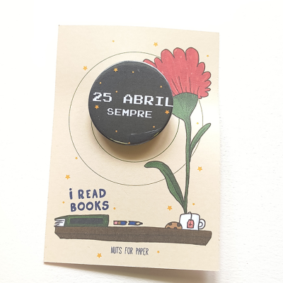 Botão 25 ABRIL SEMPRE em cartão decorativo com flor e livros.