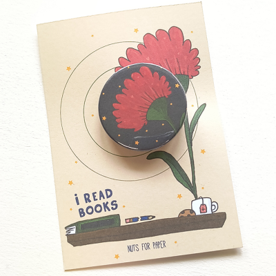 Fita adesiva decorativa com padrão de flor vermelha sobre cartão ilustrado com flores e livros.