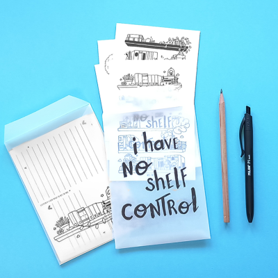 Conjunto de blocos de papel ilustrados com frases e desenhos de comboios, lápis de madeira e caneta preta sobre fundo azul.