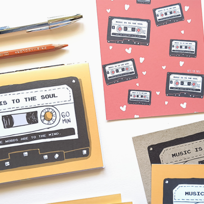 Cadernos com ilustração de fitas cassete e texto sobre a música, lápis, pincel, folha decorativa e fitas adesivas