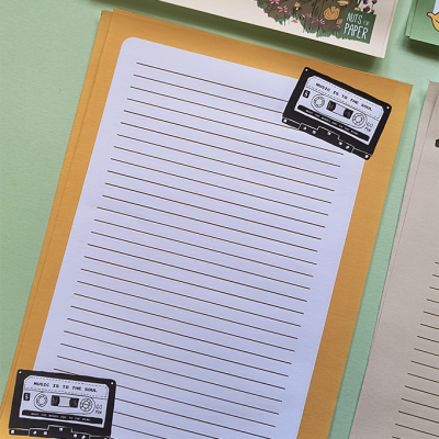 Papel de carta com linhas e ilustrações de cassetes em fundo amarelo-alaranjado