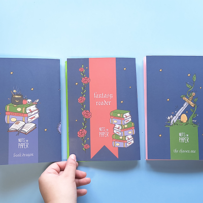 Três cadernos coloridos com capas ilustradas e textos em inglês sobre livros e leitura