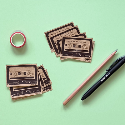 Etiquetas de cassete de papel, fita adesiva, lápis e caneta sobre superfície verde clara