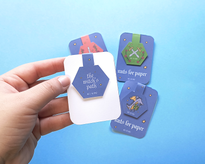 Quatro cartões azuis com ilustrações místicas e texto, um segurado por uma mão sobre fundo azul