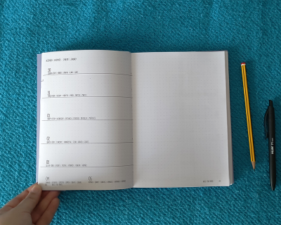 Caderno aberto com tabela semanal de 04 a 10 JUN, páginas pontilhadas, lápis amarelo e caneta preta ao lado