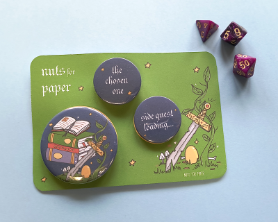 Bottons pretos com texto e ilustrações sobre cartão verde e três dados roxos e dourados num fundo azul claro.