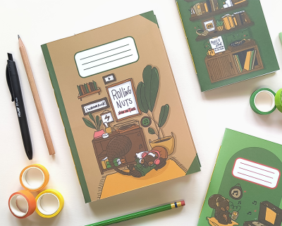 Cadernos ilustrados com desenhos de interiores e um urso, com vários objetos de papelaria ao redor.