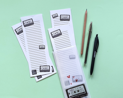 Blocos de notas com cassetes e canetas sobre fundo verde claro