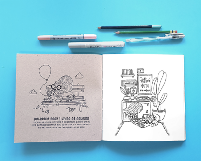 Livro de colorir aberto com desenhos a preto e branco e material de desenho azul no fundo