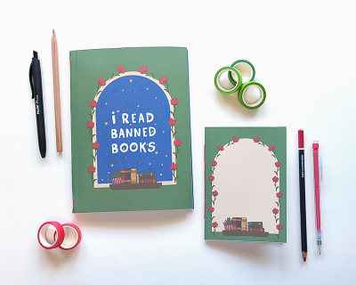 Dois cadernos verdes com ilustrações de livros e texto, canetas, lápis e fitas adesivas num fundo branco