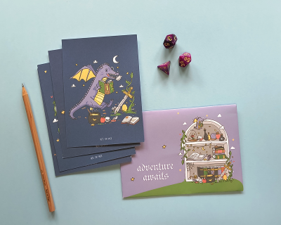 Cadernos ilustrados, lápis e dados coloridos sobre fundo azul claro