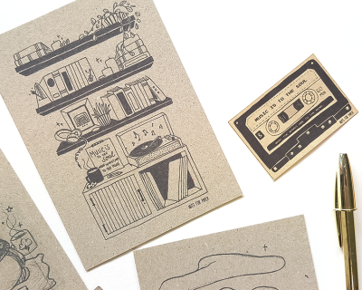 Cartões postais com desenhos e textos sobre música, e caneta dourada