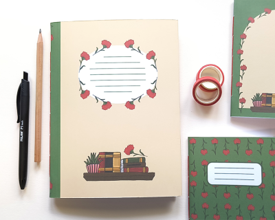 Cadernos decorados com livros e flores vermelhas ao lado de caneta, lápis e fita decorativa