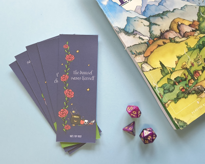 Marcadores de livro roxos com ilustrações e texto, três dados poliedros roxos com números dourados, e parte da capa de um livro ou jogo colorido.