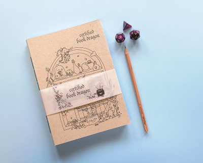 Conjunto para jogos com caderno, dado e lápis sobre fundo azul claro.