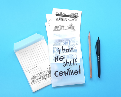 Conjunto de blocos de papel ilustrados com frases e desenhos de comboios, lápis de madeira e caneta preta sobre fundo azul.