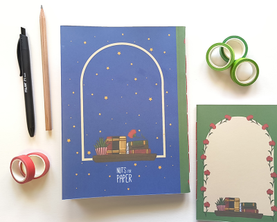 Material de papelaria com cadernos ilustrados, fitas adesivas, lápis e caneta preta