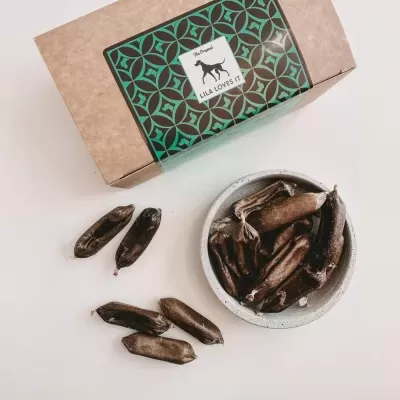 Caixa com rótulo THE ORGANIC LILA LOVES IT e frutos secos castanhos em tigela e dispersos a seu lado