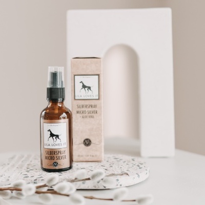 Frasco de spray de prata nano e caixa associada sobre suporte branco decorado