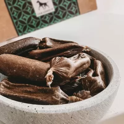 Enchidos escuros numa tigela cinza com caixa ao fundo