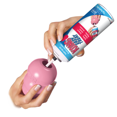 Dispensador de snacks para cães rosa e embalagem de recheio KONG Easy Treat nas mãos