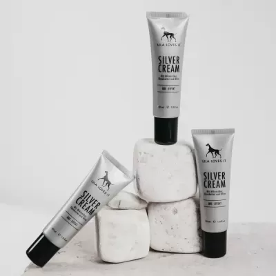 Três tubos de Silver Cream da Lila Loves It dispostos sobre cubos de pedra branca