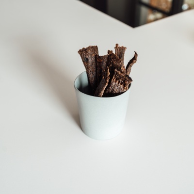 Pedaços de carne seca dentro de copo branco sobre superfície branca