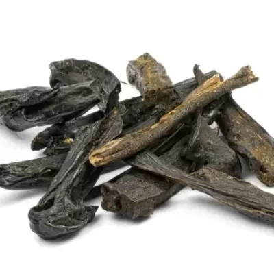 Pedaços secos e escuros de alcaçuz sobre fundo branco