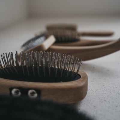 Escovas de cabelo com corpo em madeira e cerdas metálicas numa superfície clara