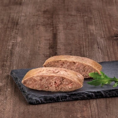 Dois pães recheados com pasta de carne rosa em placa de ardósia e folha verde sobre madeira