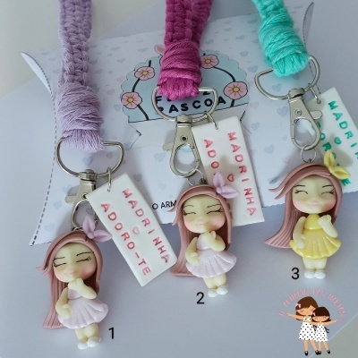 Três porta-chaves coloridos com figuras de menina e etiquetas com texto para madrinha.