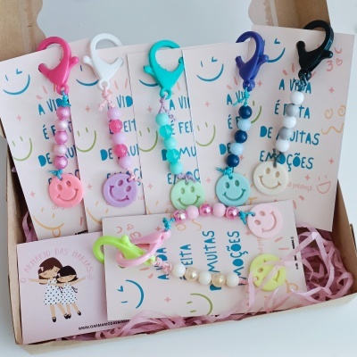 Conjunto de porta chaves com contas coloridas e smileys em cartão dentro de caixa