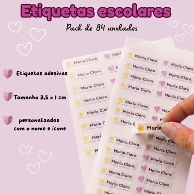 Etiquetas escolares adesivas personalizadas com nome e ícone em folhas sobre fundo rosa claro