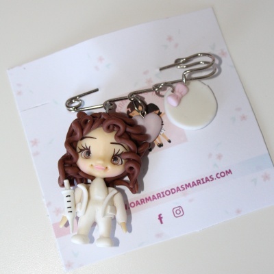 Alfinete com três pendentes, incluindo figura de personagem e detalhes em branco e rosa